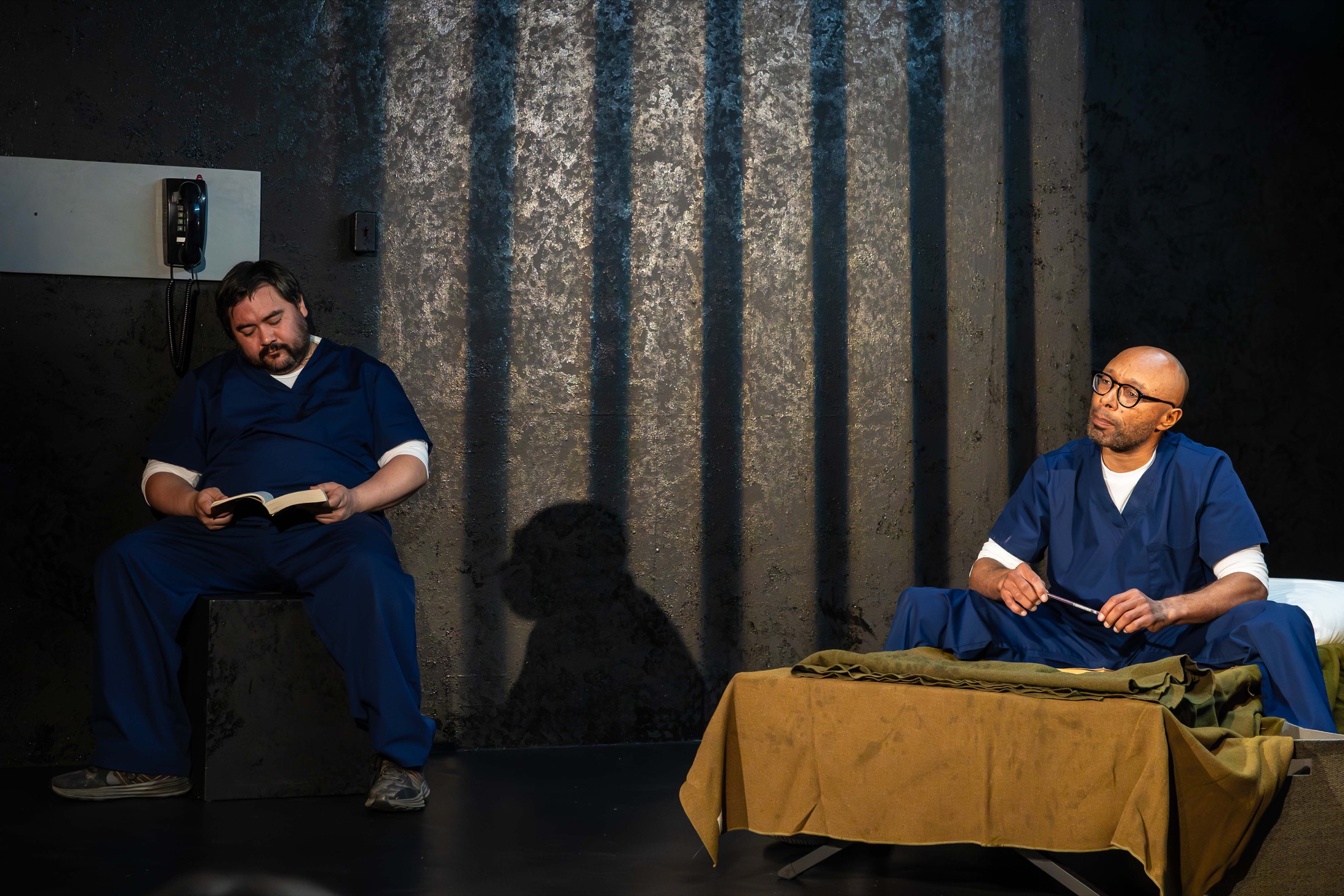 Two actors in Inside Out sit together on stage, one reading a book
